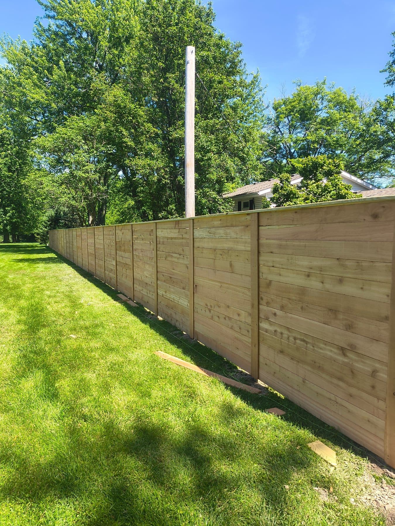 New horizontal-board wood fence along a lawn