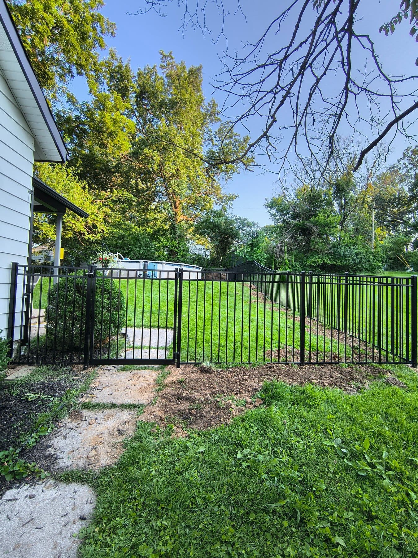 Black aluminum fence and gate beside a house