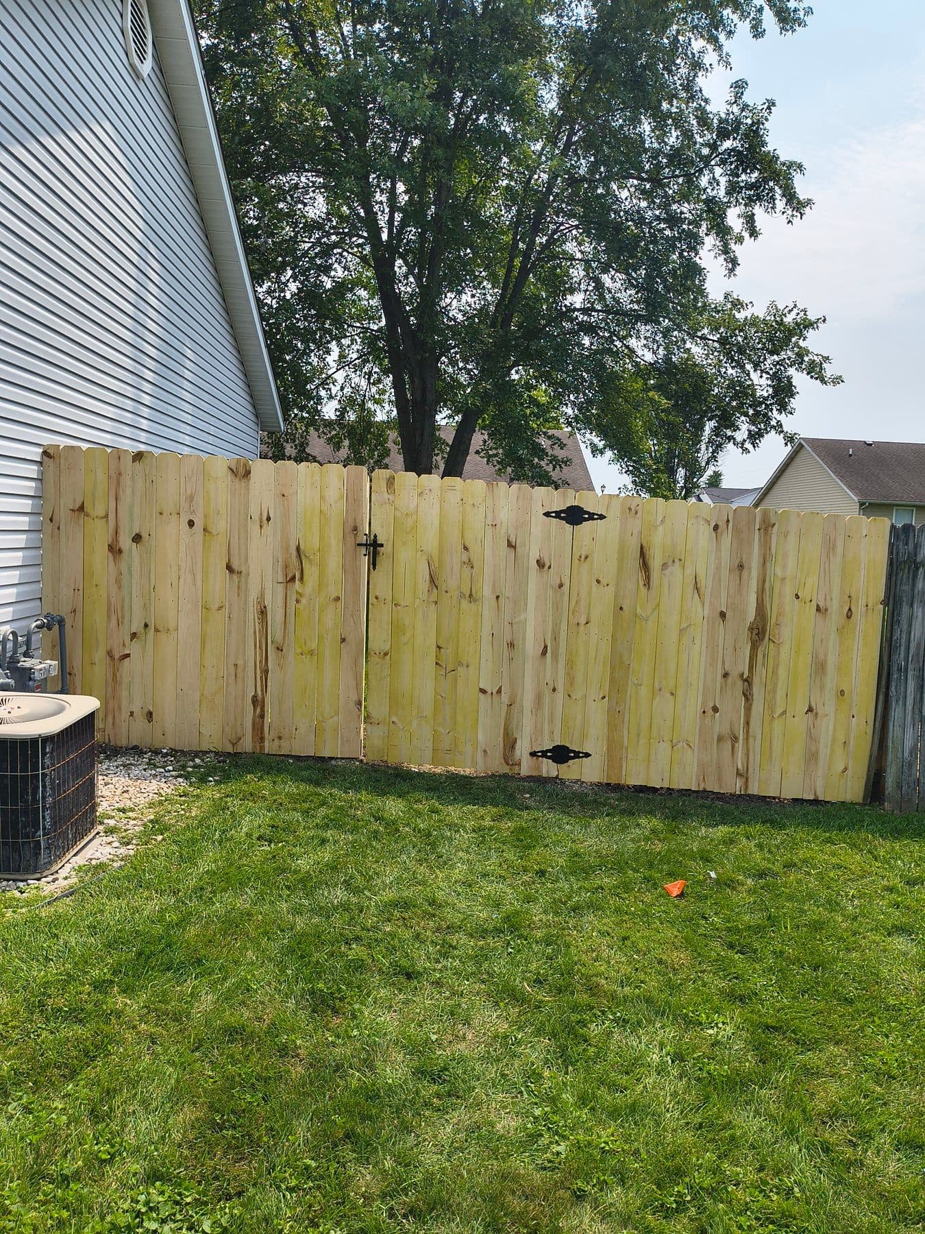 New wood privacy fence with a gate beside a house