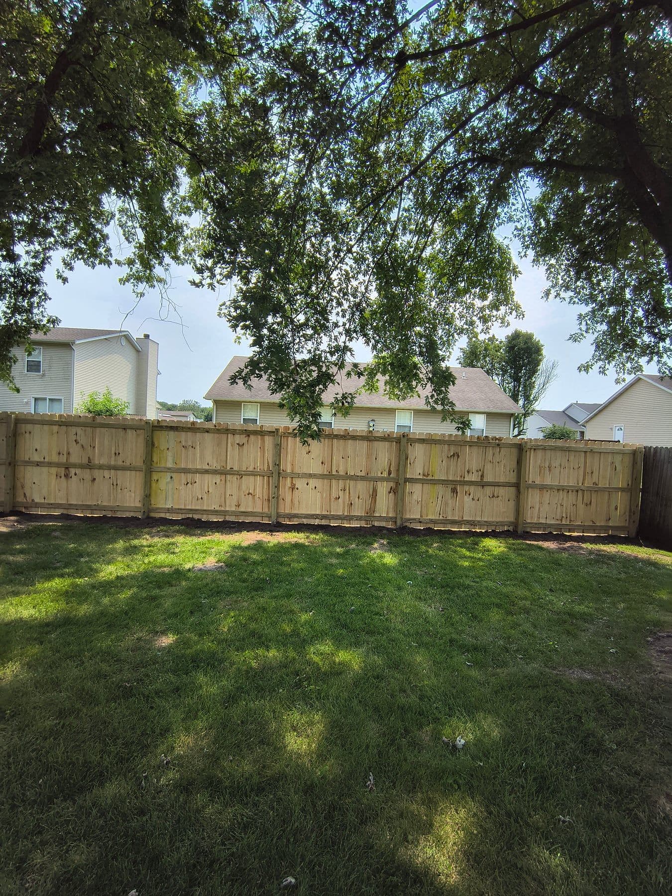 New wood privacy fence across the back of a lawn