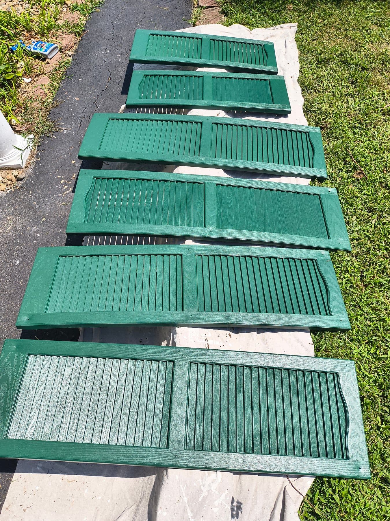 Exterior shutters freshly painted green, laid out to dry