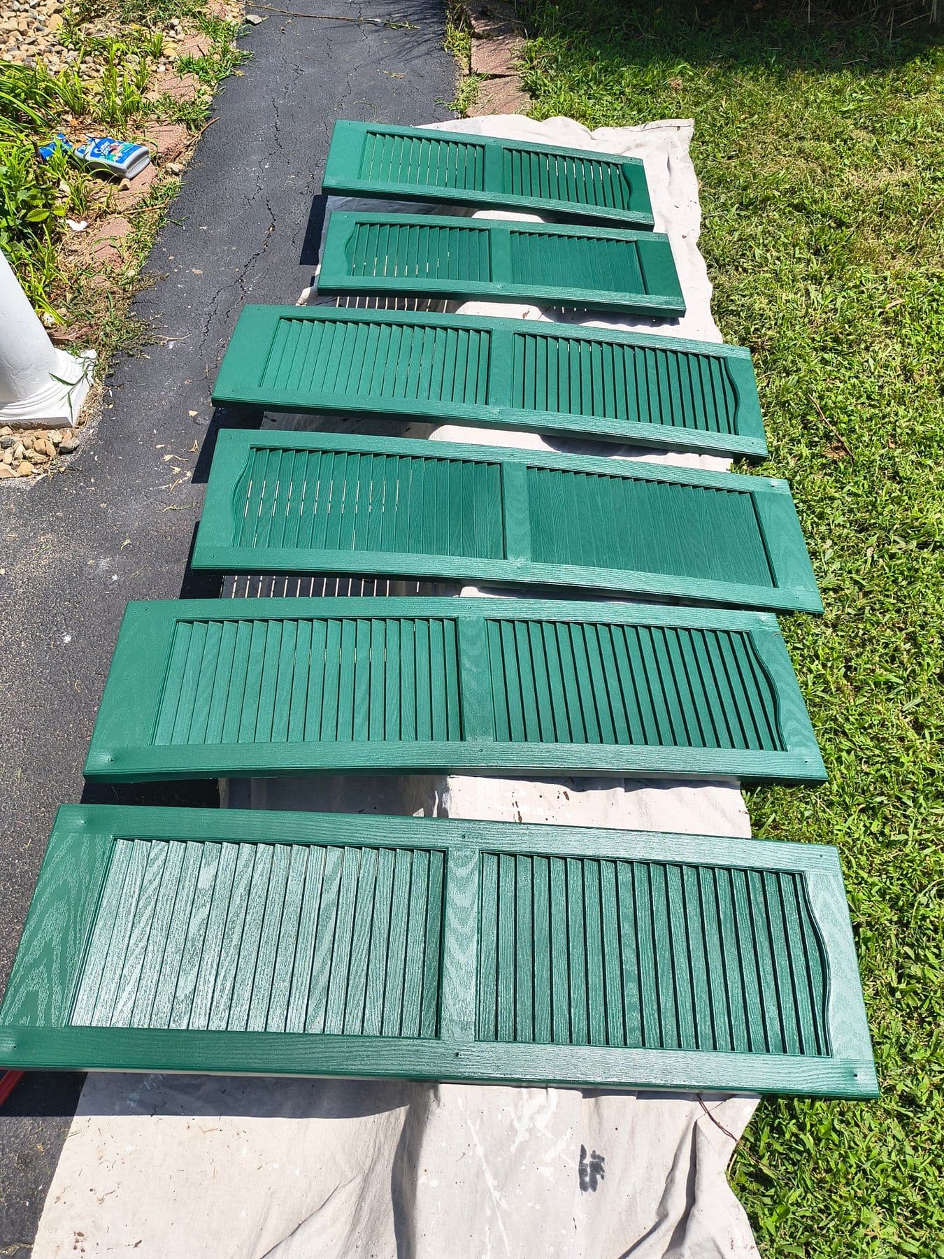 Exterior shutters painted green, drying on the lawn